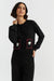 Woman wearing a black cardigan with red accents and white designs on a white background