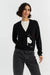 Woman wearing a black cardigan with a white graphic design on a light gray background