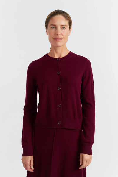 Woman wearing a burgundy cardigan and skirt set on a white background