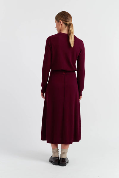 Woman wearing a burgundy dress and sweater set on a white background