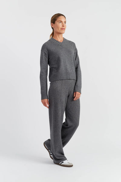 Person wearing a gray sweater and pants on a white background