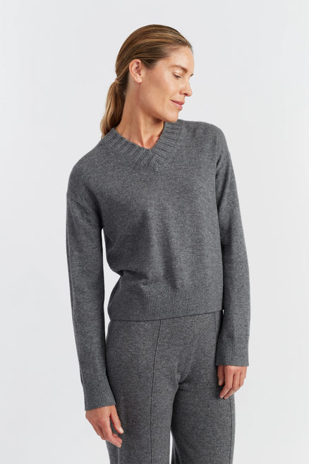 Woman wearing a gray sweater and pants on a light gray background