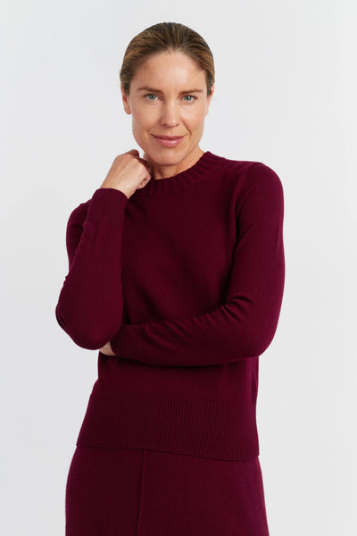 Woman wearing a burgundy sweater against a white background