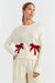 Woman wearing a white sweater with red bows on a white background
