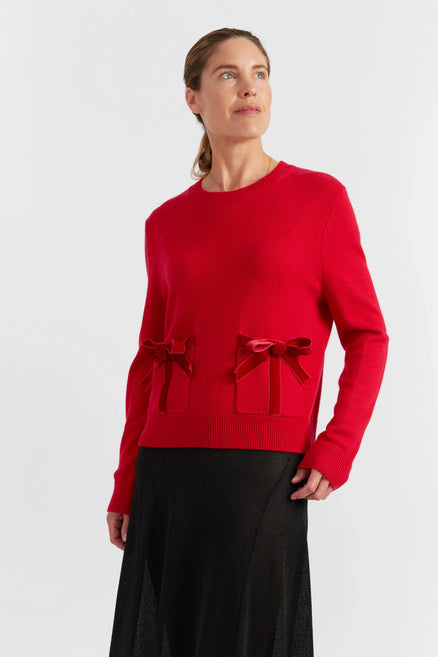 Woman wearing a red sweater with bow details on a white background