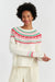 Woman wearing a white sweater with red and green pattern on a light gray background