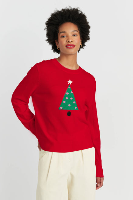 Person wearing a red sweater with a Christmas tree design on a plain background