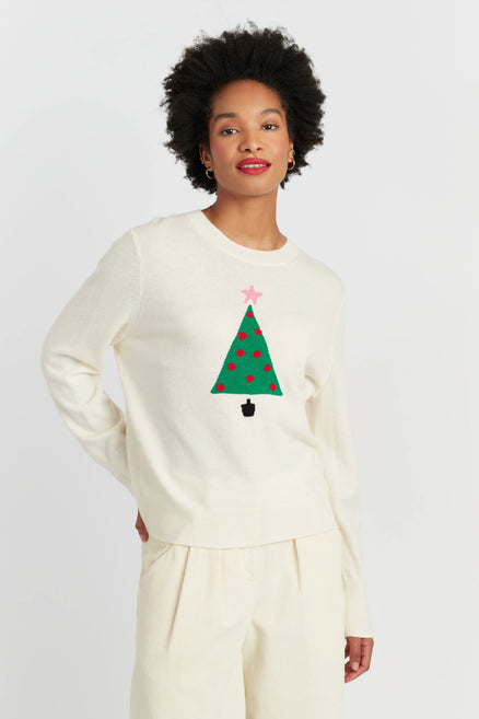 Person wearing a cream sweater with a Christmas tree design on a white background