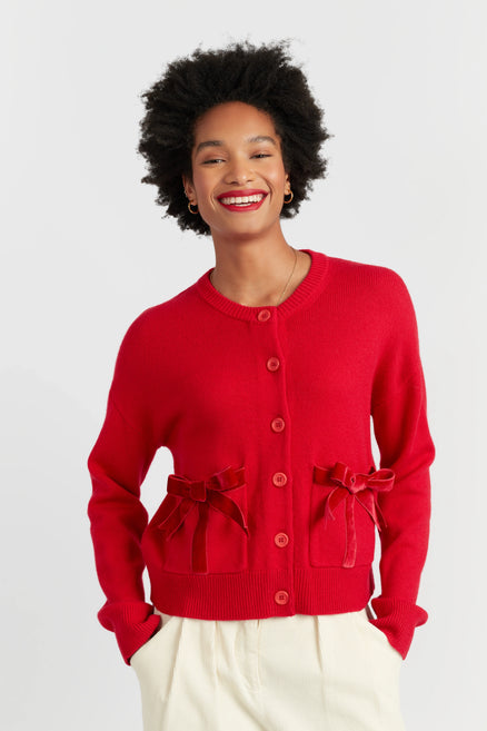 Woman wearing a red cardigan with ruffled details on a white background