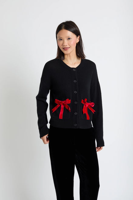 Person wearing a black outfit with red bows on a white background