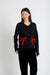 Person wearing a black outfit with red bows on a white background