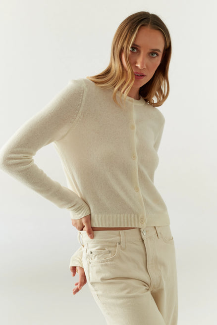 Woman wearing a beige sweater and pants against a white background