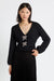 Woman wearing a black sweater with bow embellishments on a white background
