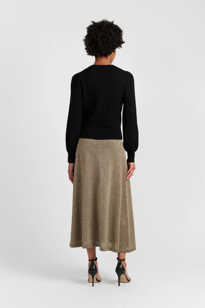 Person wearing a black top and beige skirt on a white background
