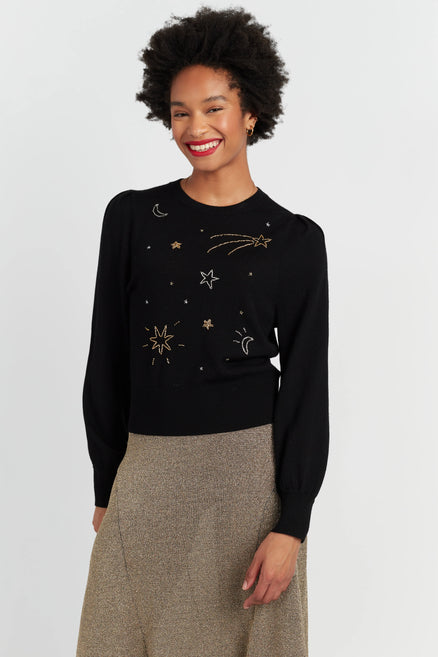 Woman wearing a black sweater with celestial designs on a white background