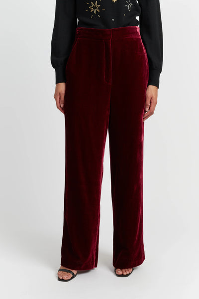 Maroon velvet pants worn by a person on a white background