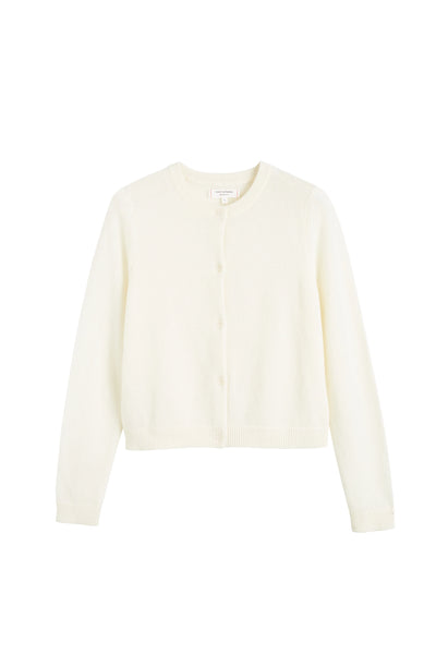 Woman wearing a beige sweater and pants against a white background