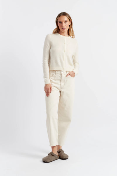 Woman wearing a beige sweater and pants against a white background
