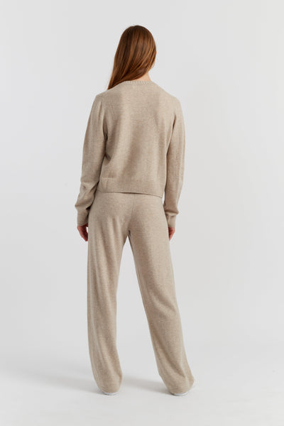 Person wearing a beige sweater and pants set on a white background