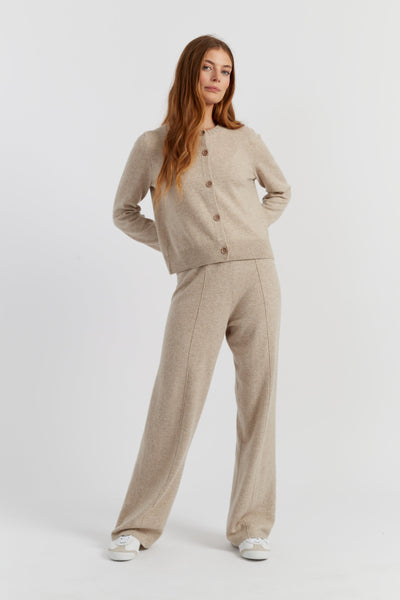 Woman wearing a beige cardigan and pants on a white background