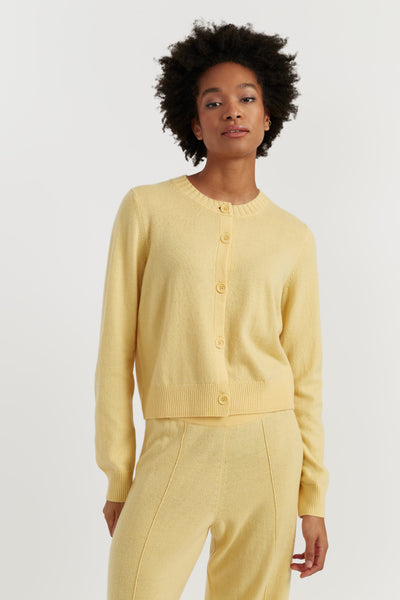 Woman wearing a yellow cardigan and pants against a white background