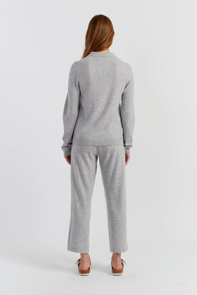 Person wearing a grey sweater and pants set on a white background