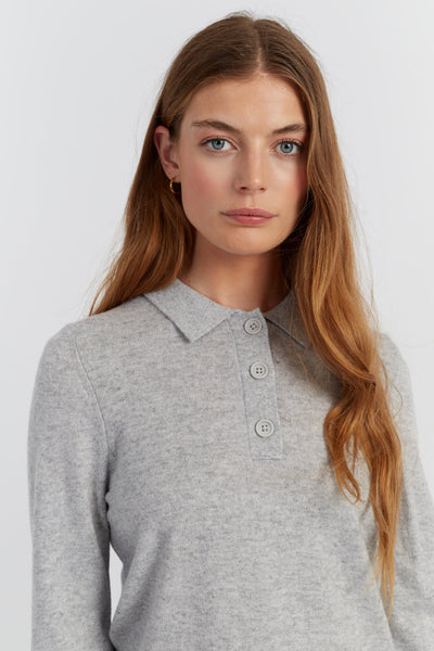Woman wearing a grey long-sleeve polo shirt against a white background