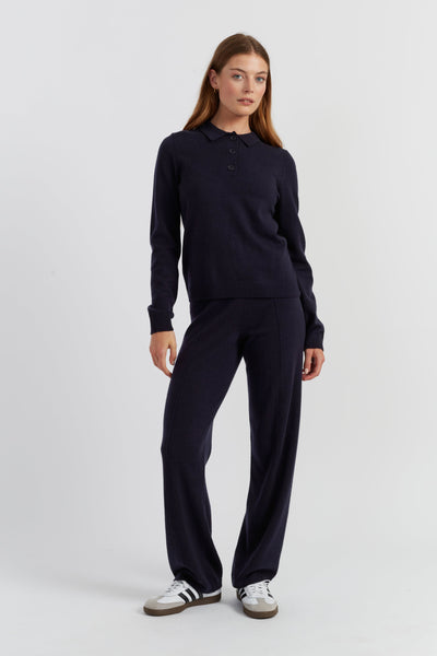 Woman wearing a navy long-sleeve shirt and pants on a white background