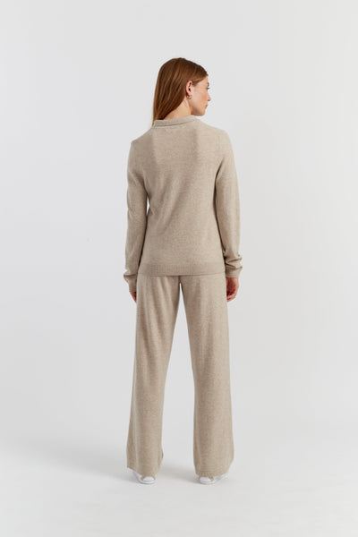 Woman wearing a beige sweater and pants set on a white background