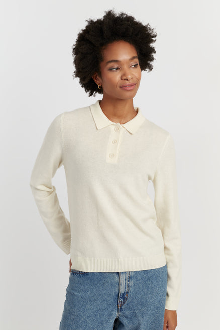 Woman wearing a cream sweater with a collar against a white background