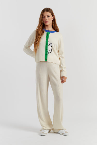 Woman wearing a cream-colored outfit with a graphic design on a white background