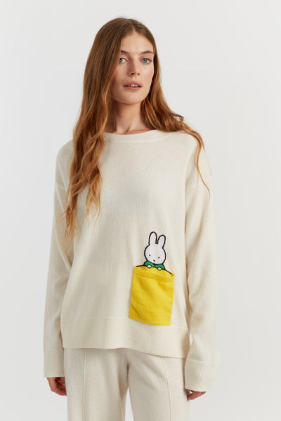 Woman wearing a cream sweater with a cartoon character design on a white background