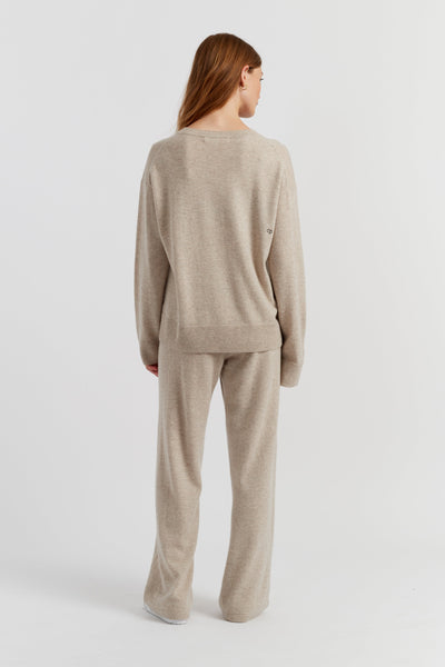 Woman wearing a beige sweater and pants set on a white background