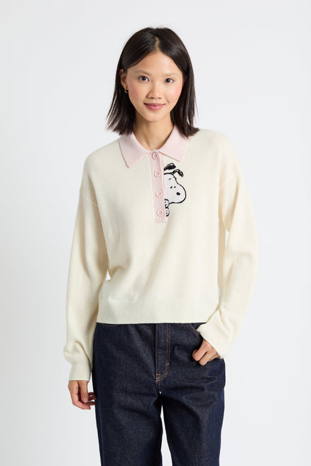 Woman wearing a cream-colored polo shirt with a graphic design on a white background