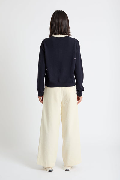 Person wearing a navy sweater and beige pants on a white background