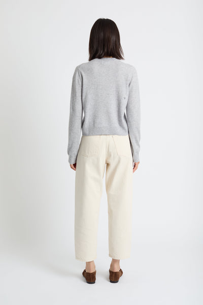 Person wearing a grey sweater and beige pants on a white background