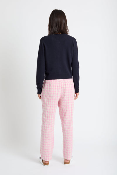 Person wearing a navy sweater and pink checkered pants on a white background