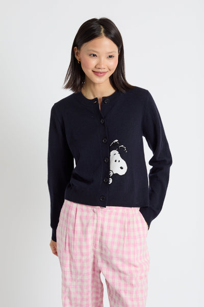 Woman wearing a navy cardigan with a white dog design and pink
 pants on a white background