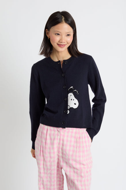 Woman wearing a navy cardigan with a white dog design and pink
 pants on a white background