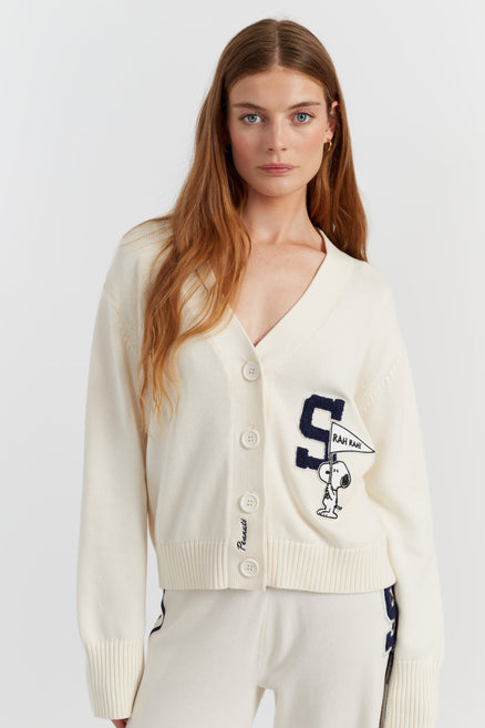 Woman wearing a cream cardigan with a logo on a white background