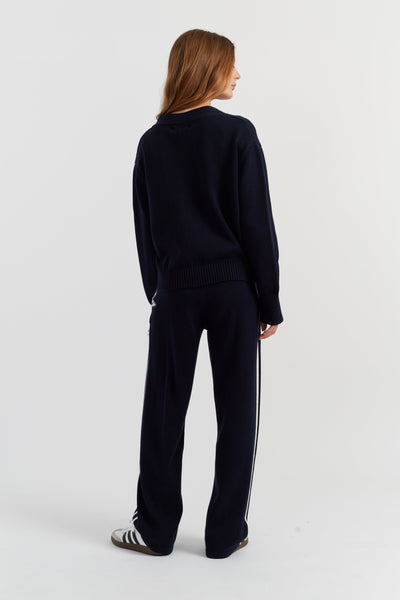 Person wearing a black tracksuit with white stripes on a light gray background