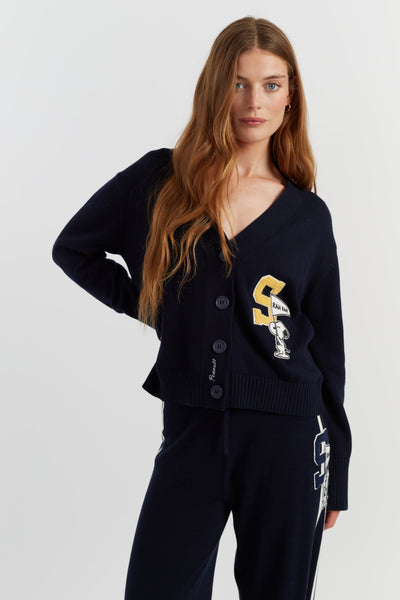 Woman wearing a navy blue cardigan with brand logos on a white background