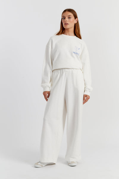 Person wearing a white outfit with a logo on a plain background