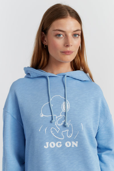 Woman wearing a blue hoodie with a snoopy design and text on a plain background