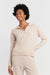 Woman wearing a light pink long-sleeve top and pants on a white background
