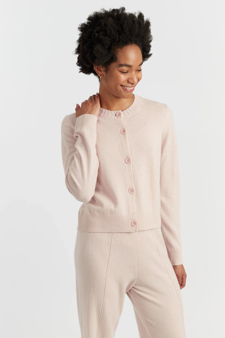 Woman wearing a light pink cardigan and pants on a white background