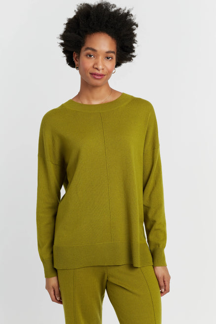 Woman wearing a green sweater and pants on a white background