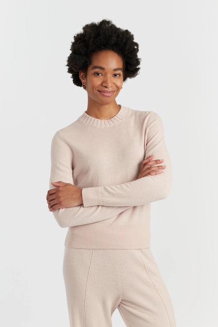 Woman wearing a beige sweater and pants on a white background