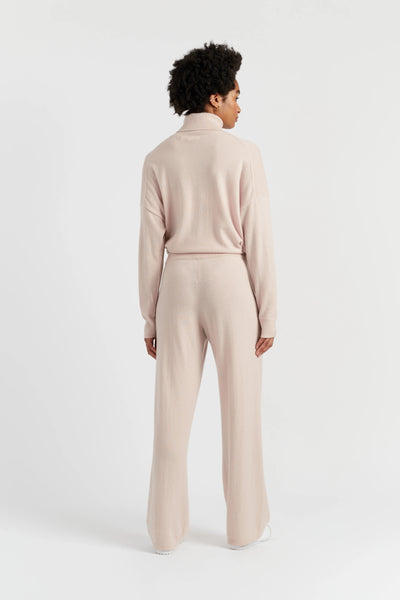 Person wearing a beige turtleneck and pants set on a white background