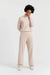 Person wearing a beige sweater and pants on a white background